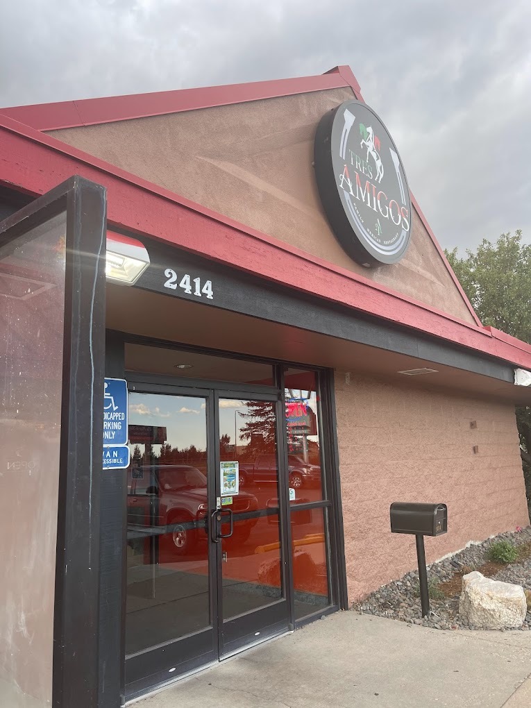 An outdoor view of a resturaunt with a red roof, and a black sign over the set of glass dor