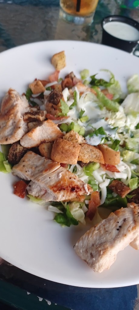 A white plate consisting of chicken on top of a salad.