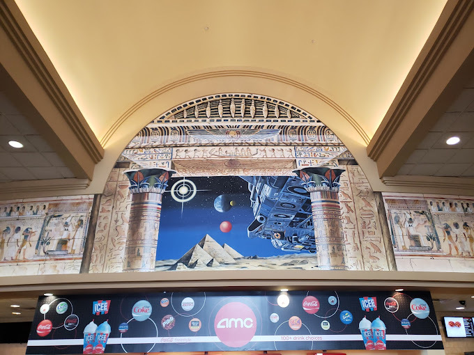 A view of a mural above a movie theater concession stand counter- an Egyptian and space scene is depicted on the wall.