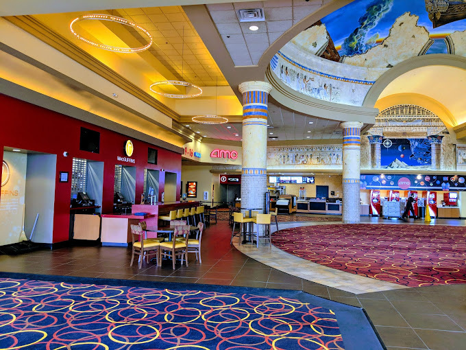 An inside view of a large movie theatre lobby designed like an extravagant building with a mural on the ceiling.
