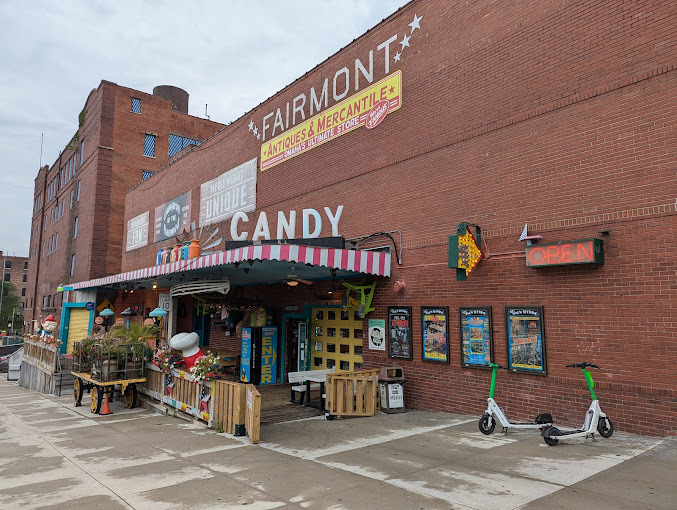 An outside view of a large brick building with a sign reading candy and another reading Fairmont.