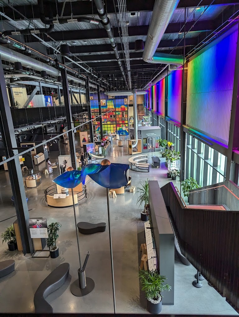 An inside view of a very colorful illuminated museum with lots of interesting art around the room.
