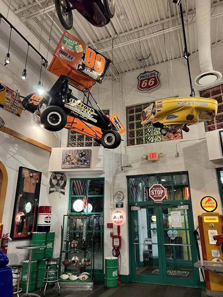 A view of a restaurant doorway with automobile memorabilia all over the walls and cars hanging from the ceiling.