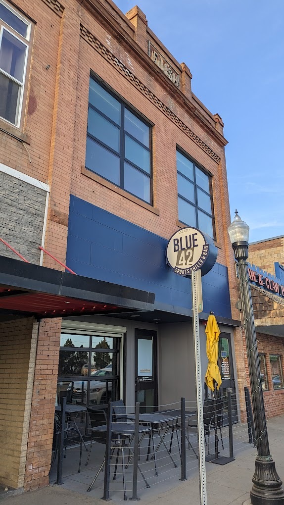 An entrance to a sports bar and grill, a restaurant with seating out front.