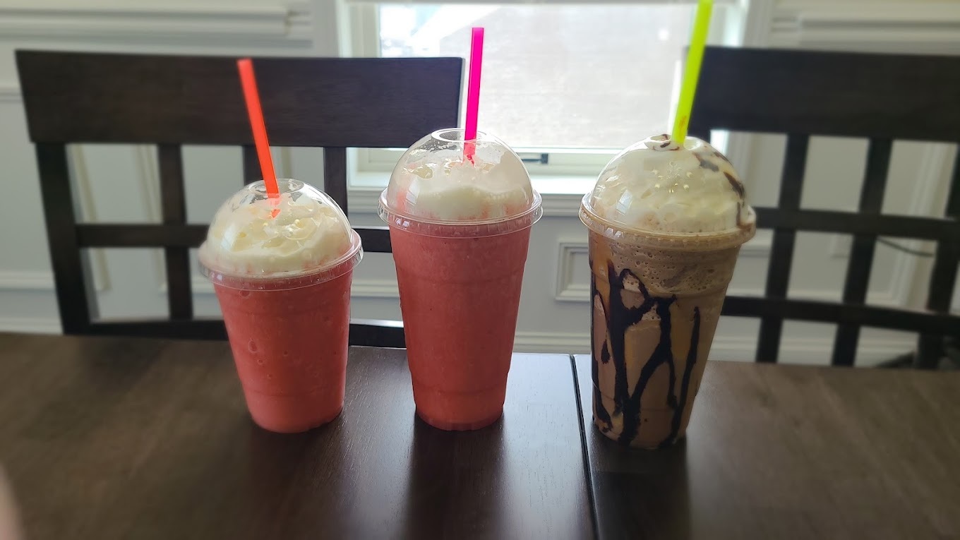 Three drinks grouped together, all blended drinks in pinks, and a chocolate drink with chocolate syrup drizzle.