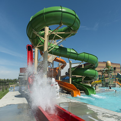 A large group of waterslides that slide into the pool below, the slides are green, red, and orange.