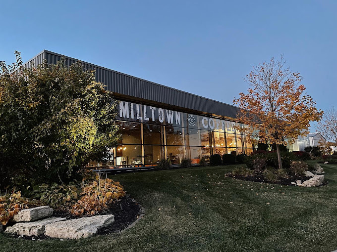 Exterior view of a dark building with huge glass windows and big trees on either side of the image.