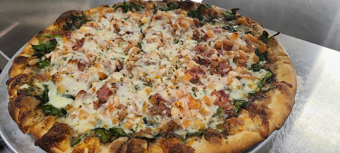 Close view of a crispy pizza on a stainless steel plate.
