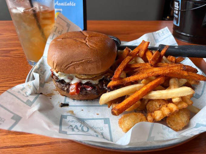 Burger and multiple fry variations in paper on a steel plate.