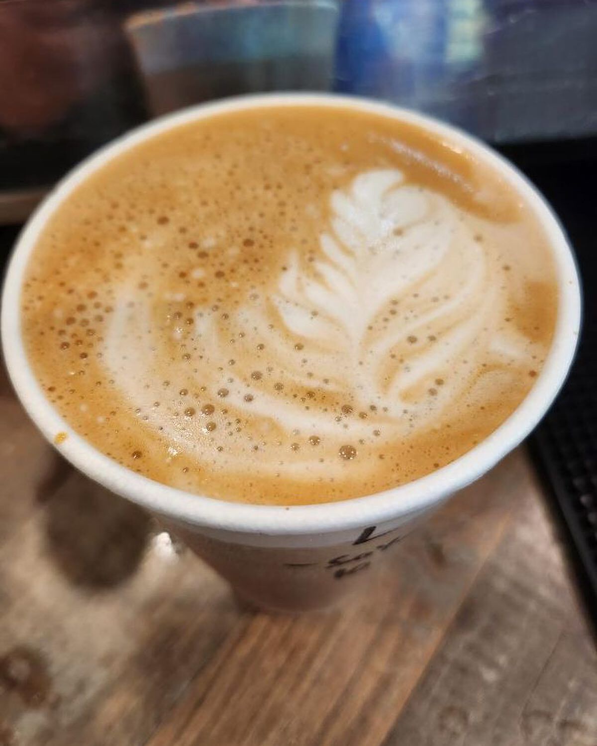 Close view of latte foam art in a white to-go cup.