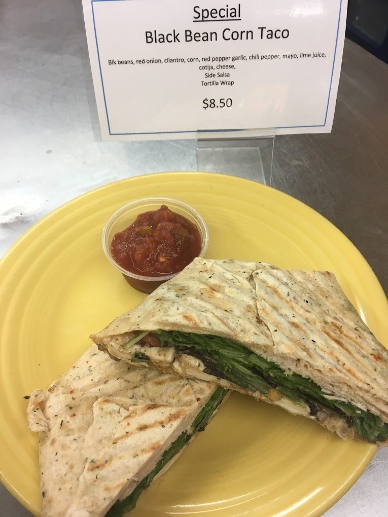 A yellow plate with a panini sandwich and a side of red sauce.