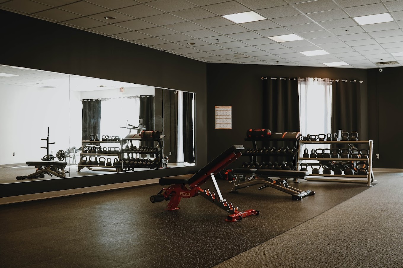An inside view of a modern, minimalistic gym, with an counter and many mirrors lining the wall.