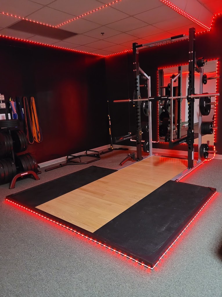 an view of a weightlifting room with LED lights lining the lifting pad.
