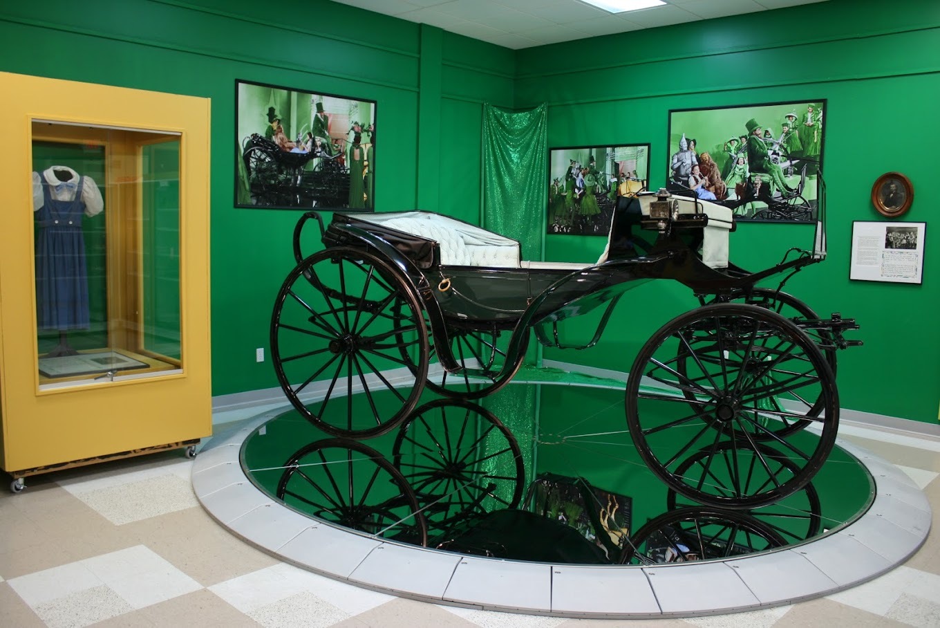 A view of a green room with an display platform showing off a carriage.