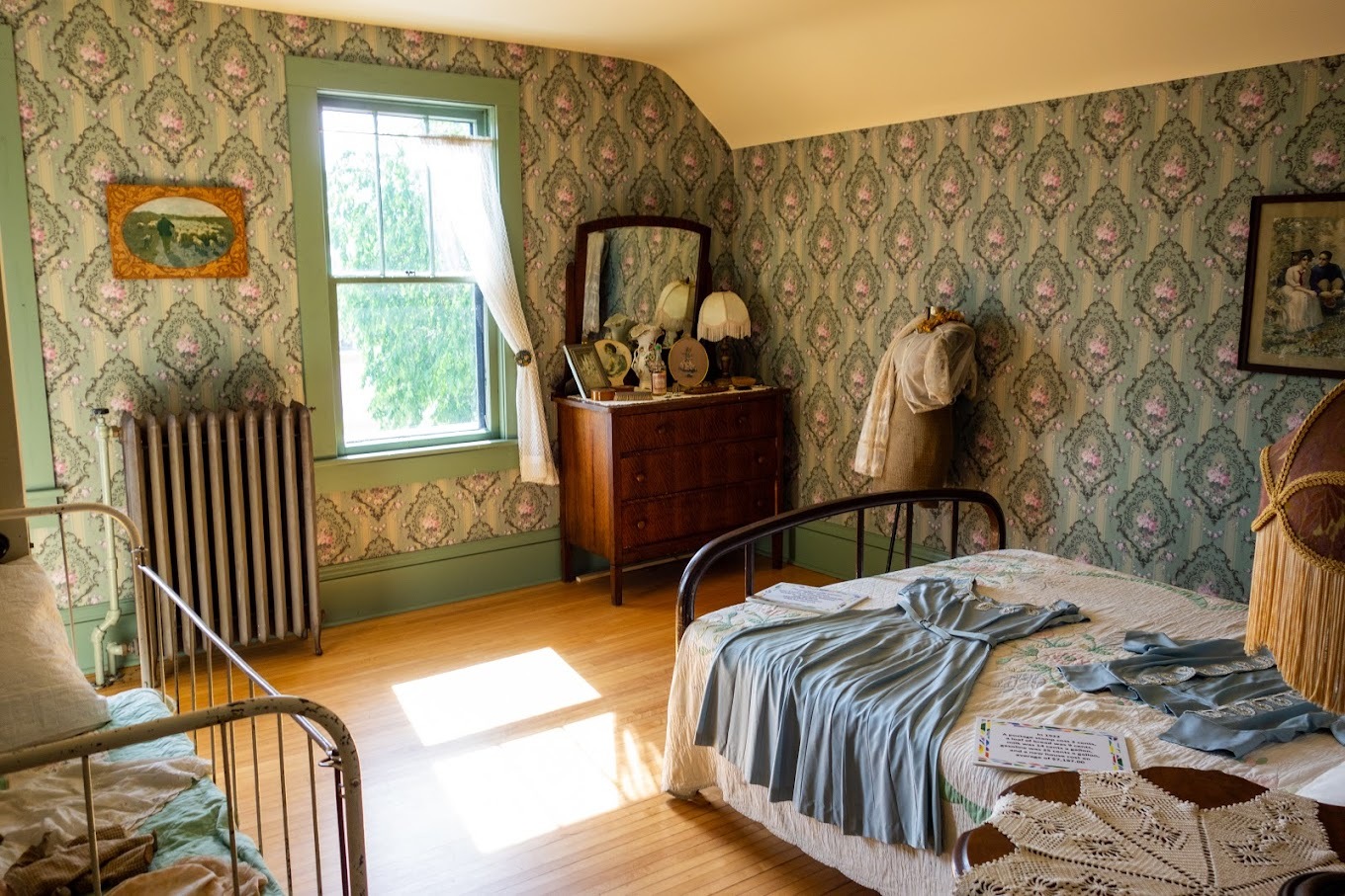 A view of an vintage bedroom, filled with antique clothing and trinkets.