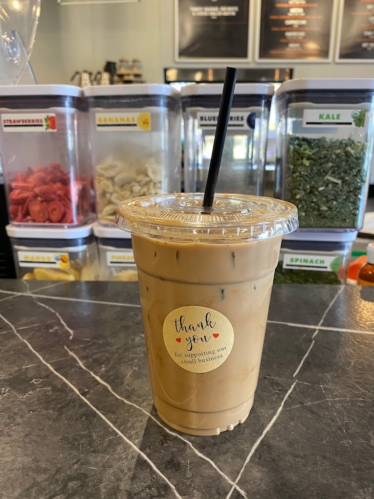 An iced coffee setting on a table with a Thank You sticker on the cup.
