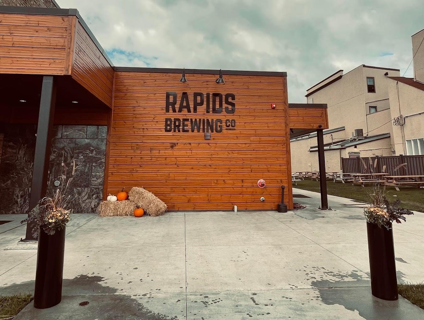 An outside view of a brewing company, a modern styled building with black lettering reading "Rapid's Brewing Co"