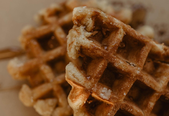 Close view of waffle piece with a full circular waffle in the background.