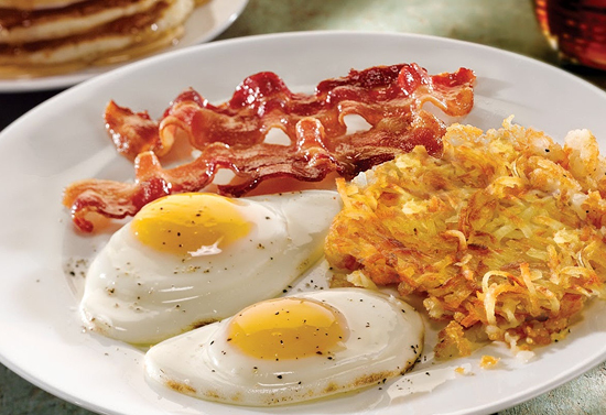 White plate of bacon, two eggs, and hashbrowns.