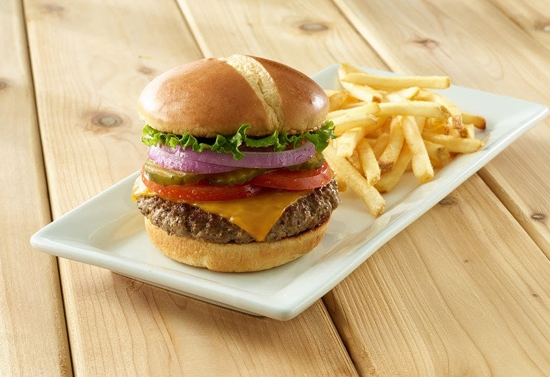 Burger and fries on a rectangular white plate set on a wooden table.