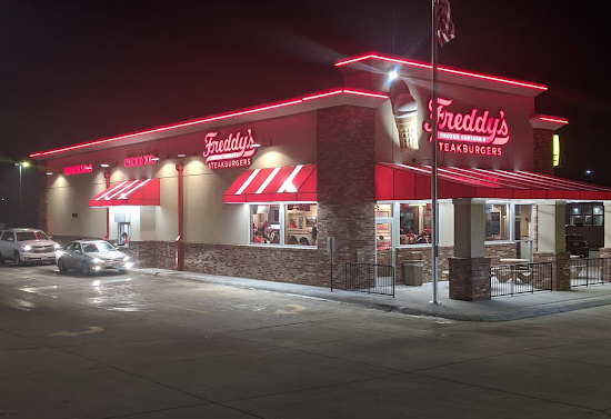 Corner view of the Freddy's building. The canopies and roof are glowing red in the dark.