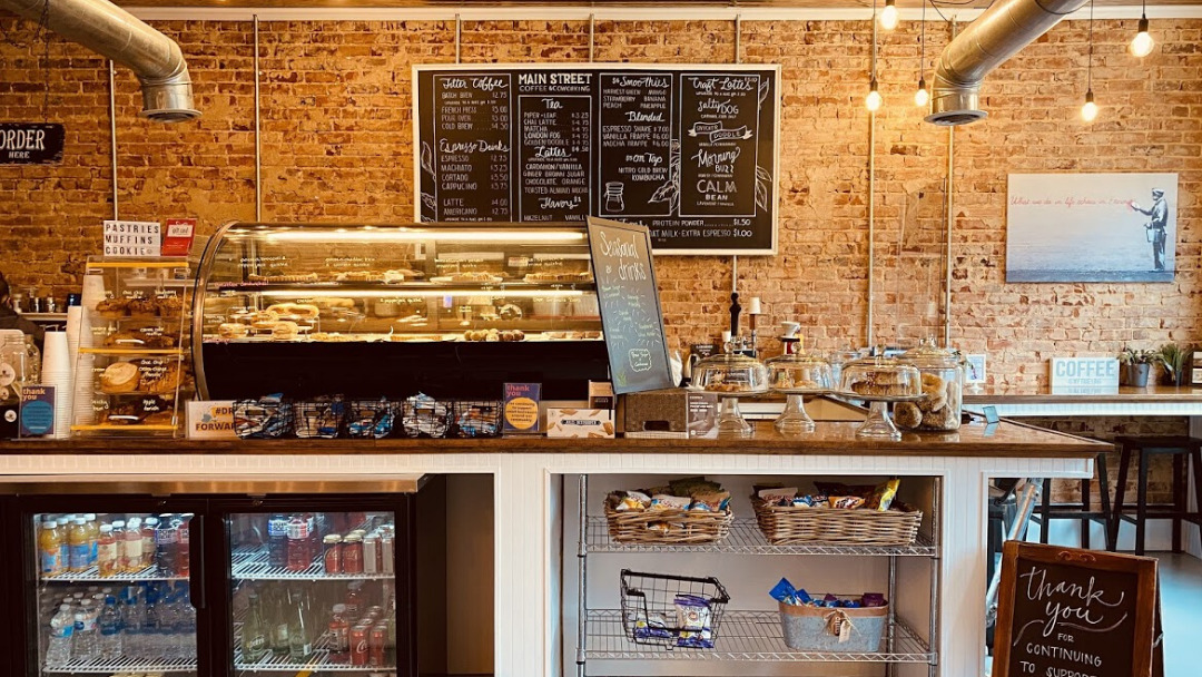 A view of a coffee counter with a display case showing off all kinds of baked goods.