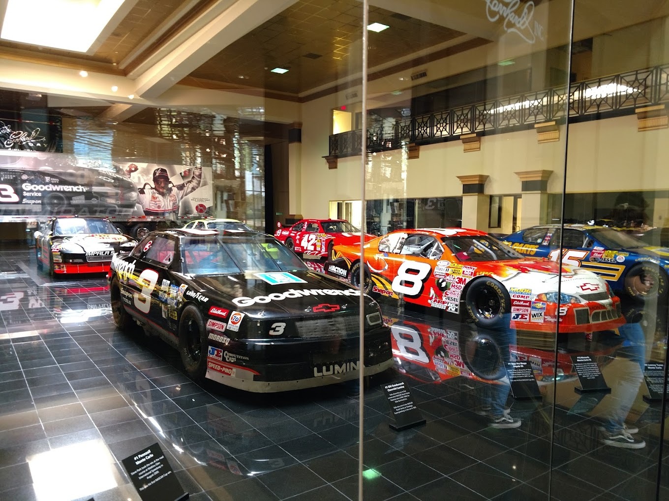 Another view of race cars on display protected behind glass.