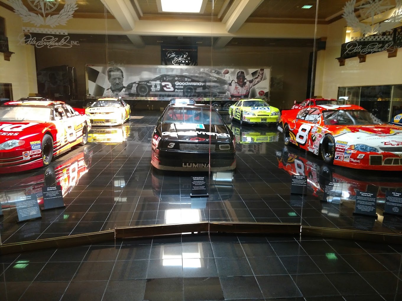 An view of race cars on display behind glass.