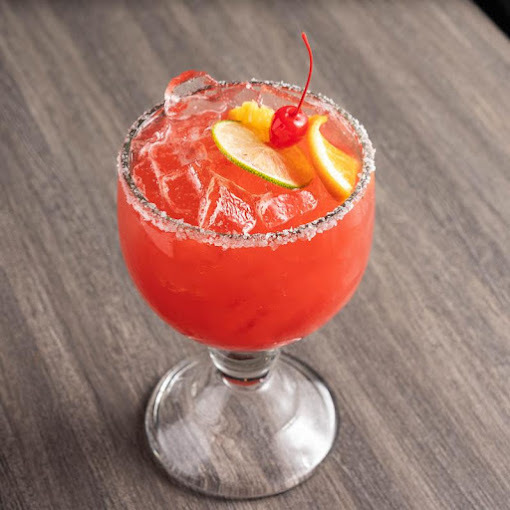 A view of an alcoholic beverage topped with a cherry garnish, lemons and a salted rim.
