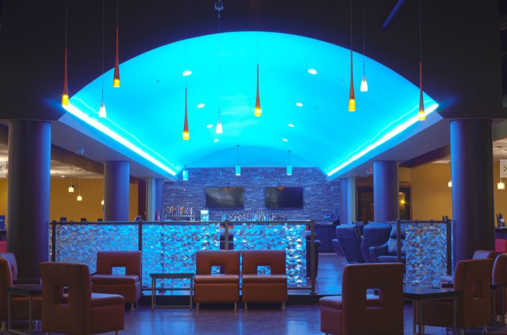 An view of a dining area that has a curved ceiling with blue lights illuminating the sides of the curved ceiling.