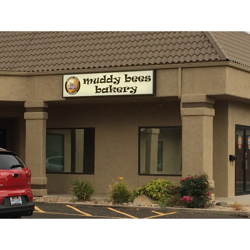 An outside view of a bakery with beige siding and a white sign above the entrance of the shop.