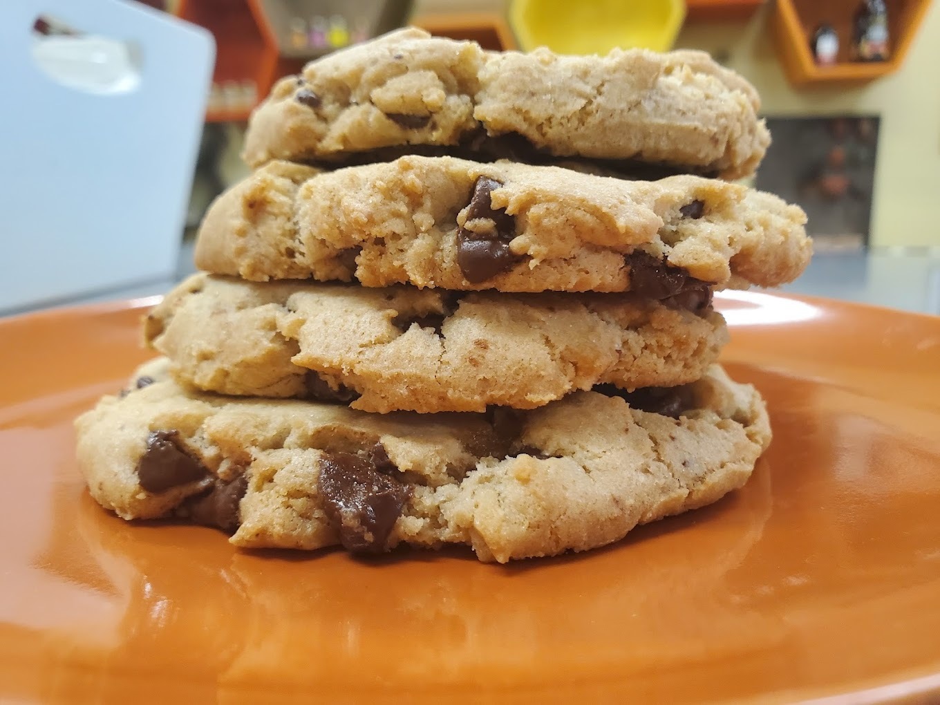 An orange plate with a stack of freshly baked cookies stacked on top of eachother.