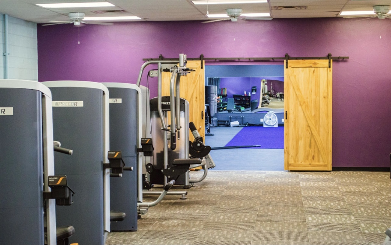 A view of a room with purple walls, filled with workout equipment.