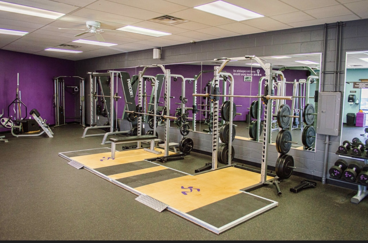A view of a gym with purple workout equipment and purple walls.