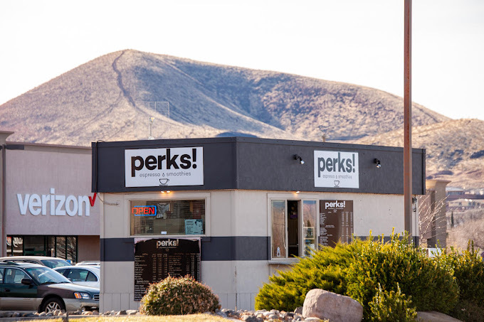 A view of a small coffeehouse building with a view of the mountains in the back.