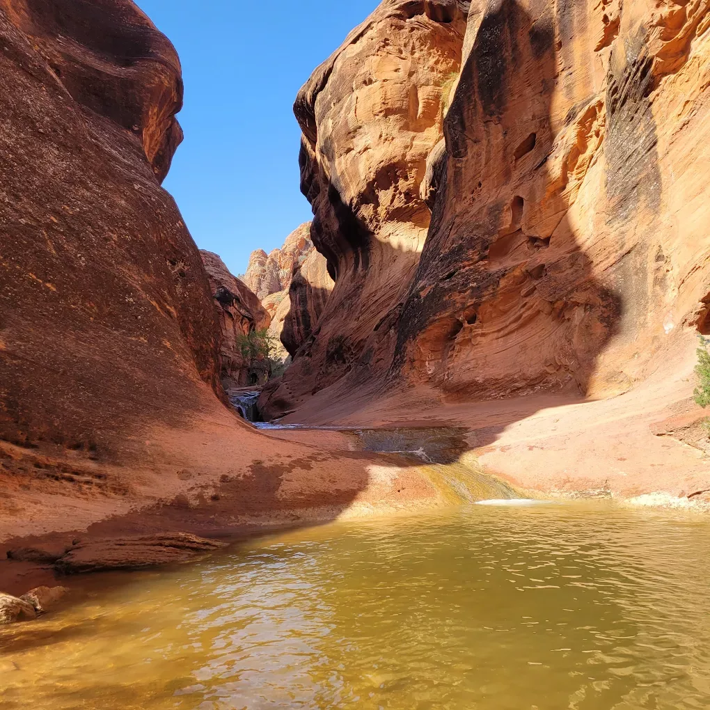 A view of a lake in a valley of very large red rock formations.