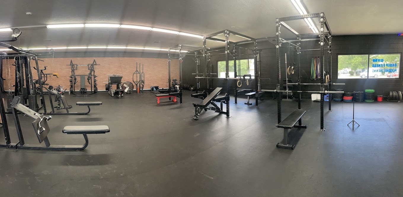 A view of a gym with black floors filled with all kinds of workout equipment.