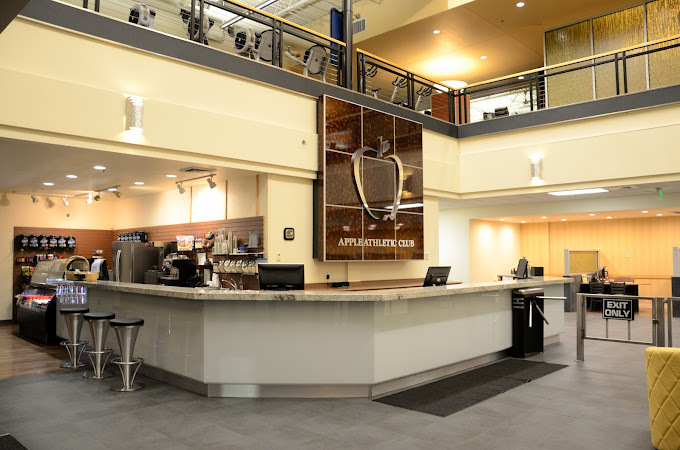 Front desk and entrance of Club Apple. A big red apple sign sits behind the desk. A balcony is at the top of the image.