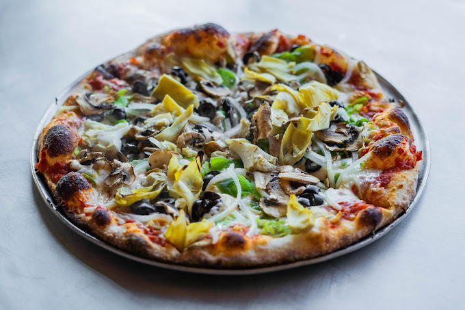 Fluffy pizza with several different toppings, such as olives, cheese, and mushrooms.
