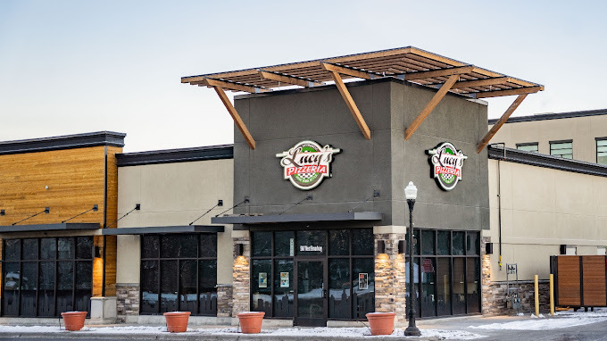 Corner view of Lucy's Pizzeria. The building corner has brown wooden canopy at the very top with several smaller black canopies directly above the windows and doors.