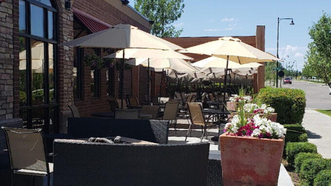 Outside sidewalk view of the restaurant.  Tables and chairs with umbrella shades.