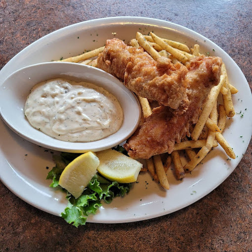Fries, chicken, and a side of sauce on a white plate.