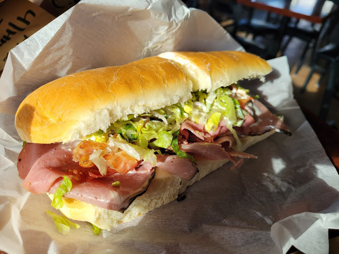 Sub with meat and greens on a white paper.