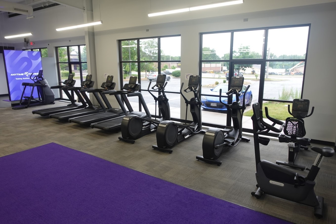 A room with purple accenting full of ellipticals and other workout machines.