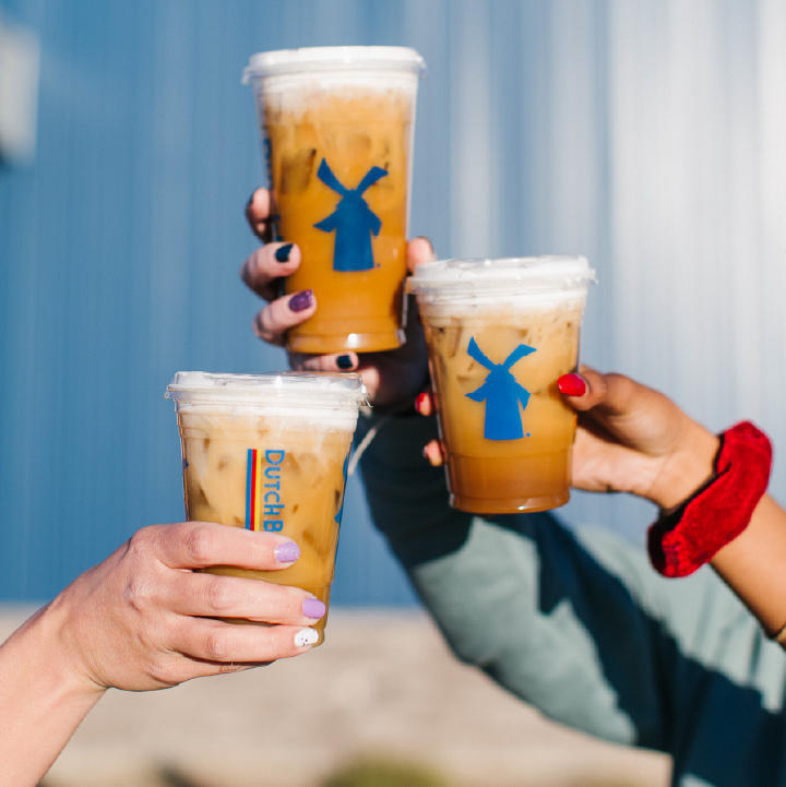 Three ladies making a cheers with their coffees in hand.