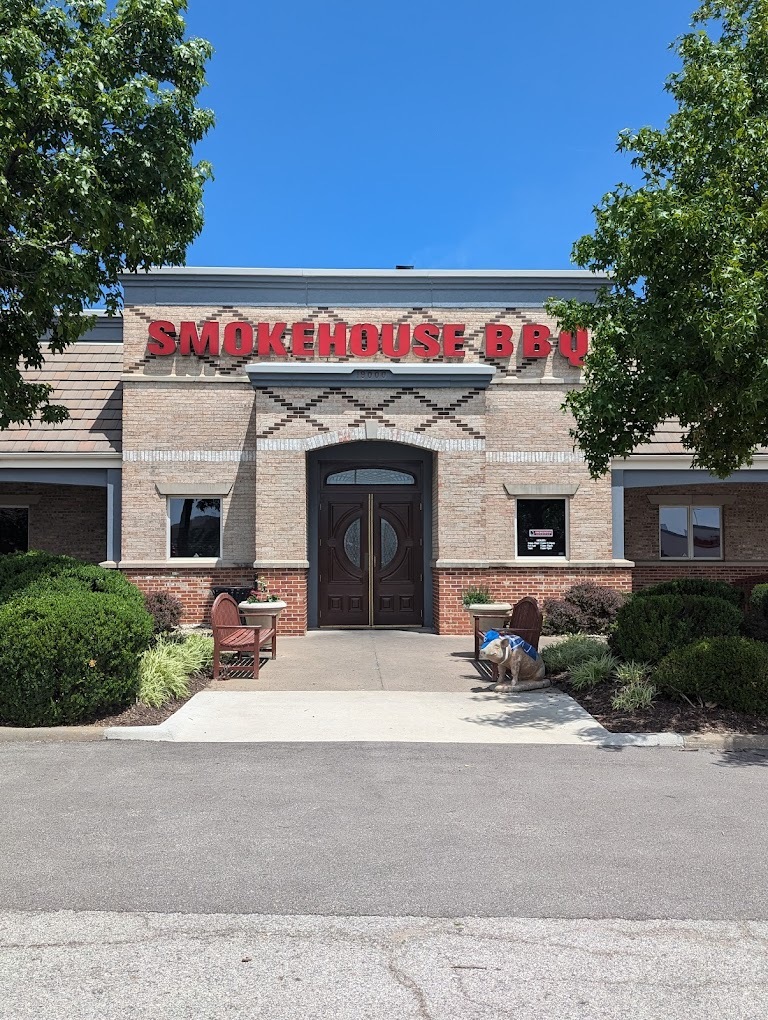 An entrance to an resturaunt with a grey brick exterior and a large red sign above the entrance that reads "Smokehouse BBQ"