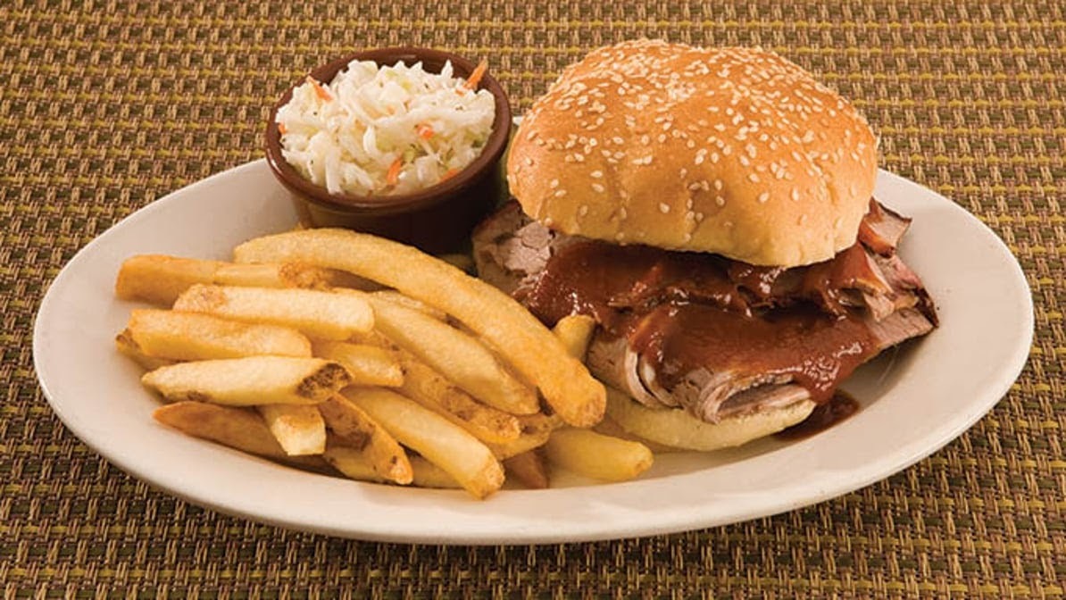White plate with a burger, classic cut fries, and a side of coleslaw.