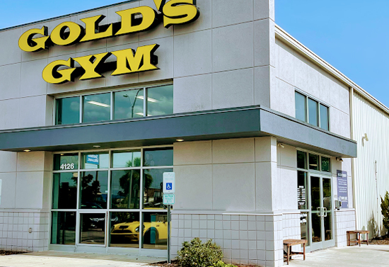 Outside corner view of a building. Sign above the door states "Gold's Gym."