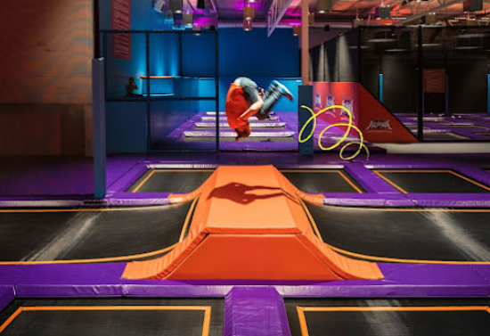 Black, orange, and purple room. Boy in the center does a flip in the air.