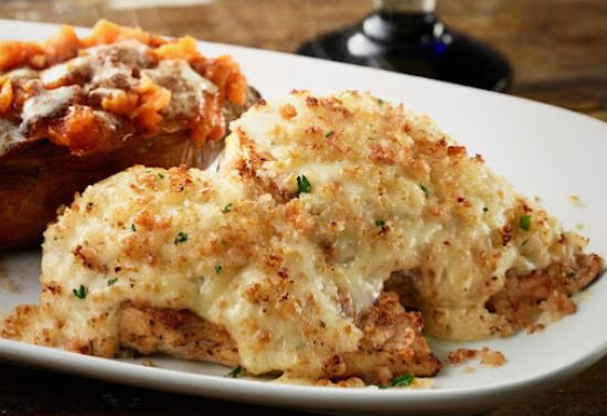 Light colored cheesy dish next to red colored dish, both on a white plate.